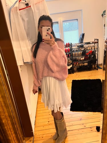 Rezensentin in einer Spiegelaufnahme mit dem weißen Rock 'Summer', kombiniert mit einem rosa Pullover und Stiefeln.