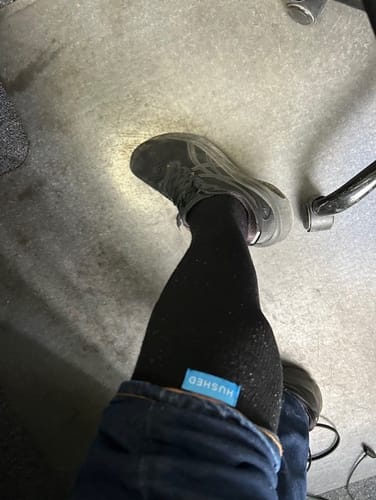 Customer wearing the black Performance Eucalyptus Compression Socks, with the blue brand tag visible above their jeans.
