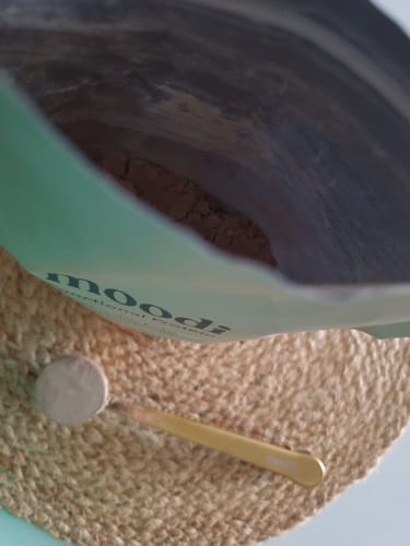 Customer's view inside the bag of Chocolate Fudge powder, with a scoop resting on a woven mat.