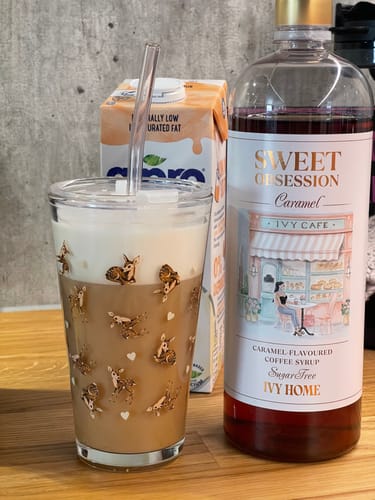 Customer's Sweet Obsession Caramel Coffee Syrup bottle next to a glass of iced coffee on a counter.