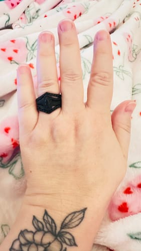Close-up of a reviewer's hand wearing the black marquise-style silicone ring from the set.