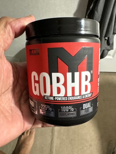 Reviewer holding a black tub of MTS Nutrition goBHB ketone supplement with a red label.