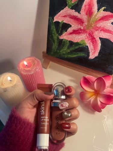 Customer holding the Peptide Lip Glaze tube and another cosmetic bottle in their hand.