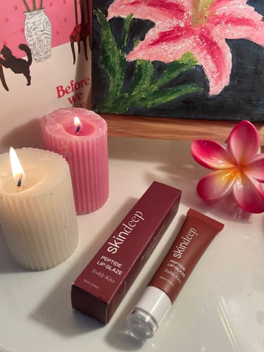 Reviewer's Peptide Lip Glaze tube shown next to its red product box on a white surface.