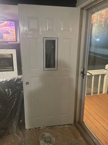 Customer's white door with the Clear 1 Lite Glass and Frame Kit installed, with blue tape around the frame for painting.