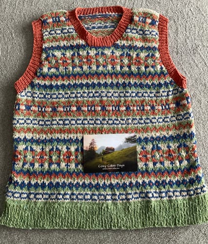 Reviewer's finished Cosy Cabin Days tank top, knitted in a colorful Fair Isle pattern with orange and green trim.