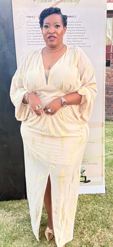 Reviewer standing outdoors in the cream Split Thigh Formal Dress with gold sequin patterns.