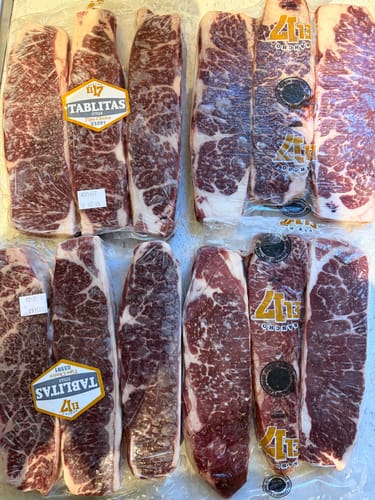 Cliente muestra varios paquetes de Tablita de Lomo cruda, sellados al vacío y con abundante marmoleo.