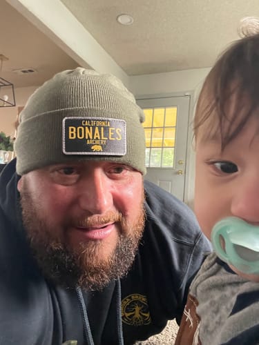 Customer wearing a green beanie featuring a custom California License Plate Swap Patch with their brand name on it.