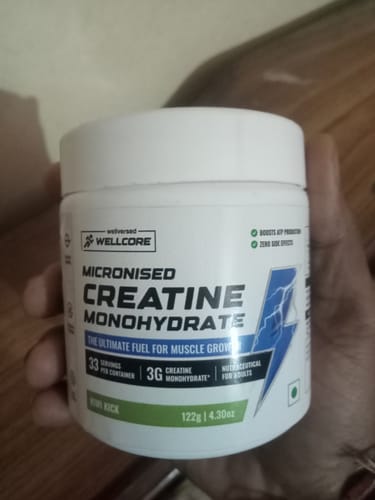 Reviewer holding a white tub of Wellcore Micronised Creatine Monohydrate.
