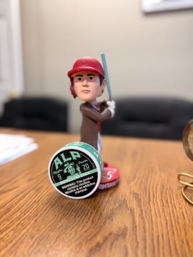 Customer's can of Refreshing Chill Nicotine Pouches on a desk next to a baseball player figurine.