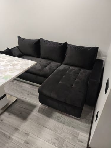 Pirkėjo juodas minkštas kampas LOKO, pastatytas kambaryje prie sienos.