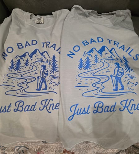 Customer's two 'Bad Knees T-shirt's laid side-by-side, showing a difference in size and print color between the orders.