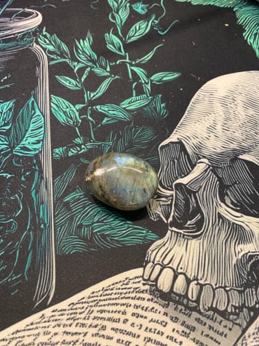 Reviewer's gorgeous monthly crystal, a polished stone with beautiful iridescent flashes, on a decorative cloth.