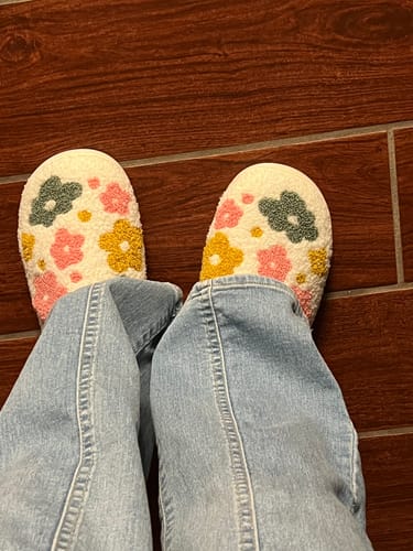 Customer's top-down view of the fluffy Livia Flower Slippers, featuring a colorful floral pattern, worn with jeans.