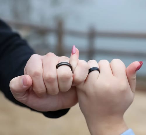 Customer showing the black Legend wedding band in a pinky promise with a partner.