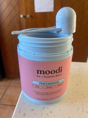 Customer's Moodi Pink Lemonade container with the reusable blue scoop resting on top.