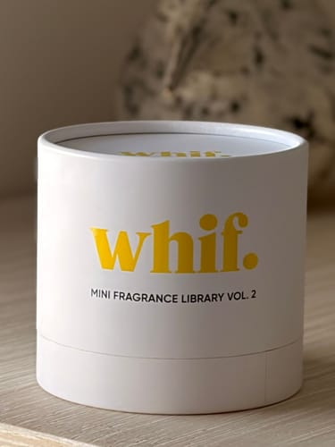 Customer's white tube packaging for the Whif Mini Fragrance Library Vol. 2 on a wooden surface.