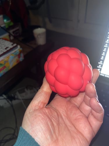 Reviewer holding the red Berri massager in their palm, showing its raspberry-like shape and size.