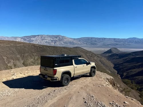 Customer's GMC Sierra with an HD Kit and camper topper parked on a mountain trail, showing a level ride height.