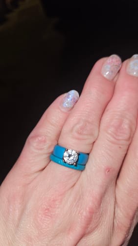 Customer's hand wearing two bright blue Infinity Silicone Rings stacked with another ring.