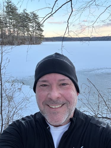 A reviewer smiles for a selfie during a trail run in a snowy landscape.