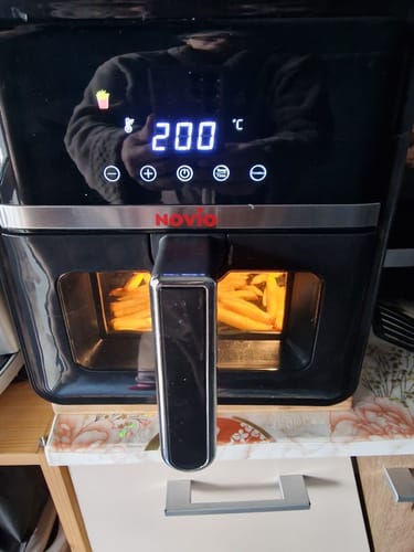Clientul arată friteuza Air Fryer Novio StonePro în funcțiune, gătind cartofi prăjiți la 200°C.