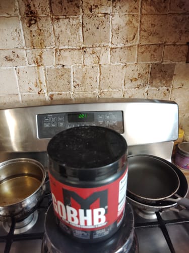 Customer's red and black tub of MTS Nutrition goBHB resting on a kitchen stovetop.
