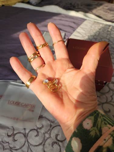 Reviewer holds the gold Diamond Lock Earrings in their palm, with several stacked rings on their fingers.