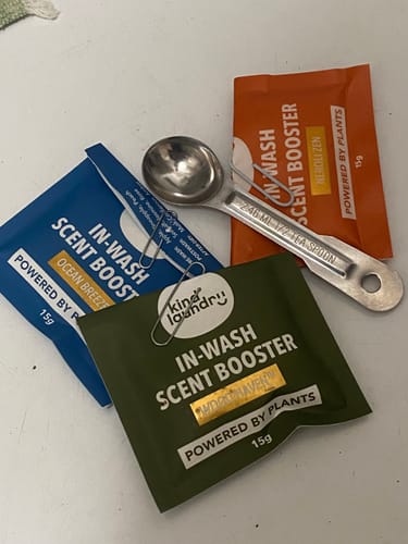 Reviewer's Scent Booster Mini Kit showing three colorful sample sachets and a half-teaspoon measuring spoon.