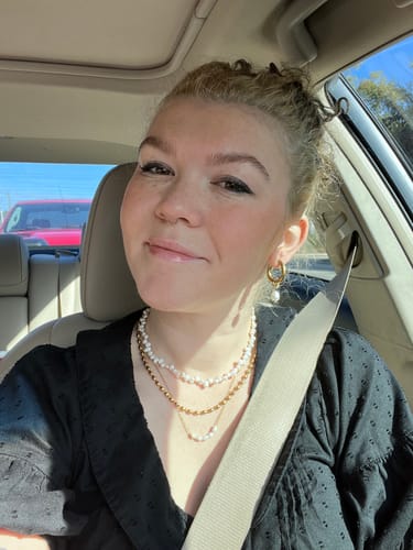 Customer wearing the layered Kona Pearl Necklace bundle with a black top while sitting in a car.