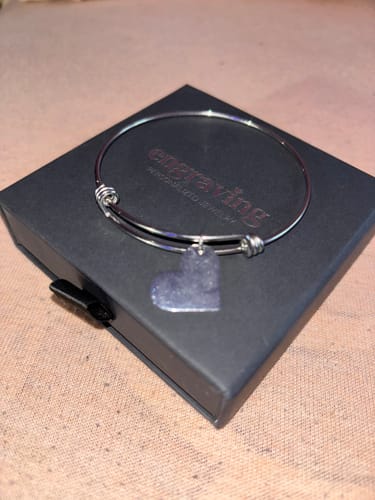 Customer's silver Heart Pendant Bracelet resting on its black presentation box.