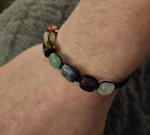 Close-up of a reviewer's wrist wearing a colorful crystal bracelet from the monthly program.