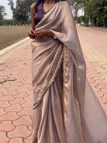 Customer wearing the elegant lavender organza satin silk saree outdoors. The flowy fabric has a visible sheen and lace border.