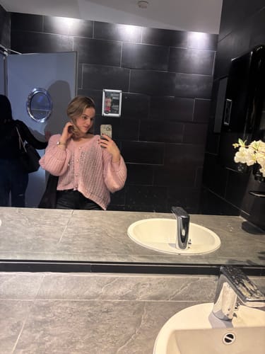 Kundin macht ein Spiegel-Selfie mit dem rosafarbenen Feinen Lochstrick Cardigan.