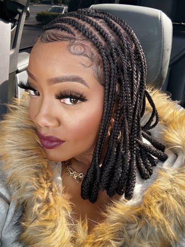 Reviewer in a car wearing the black, shoulder-length Hip braided wig with styled baby hairs.