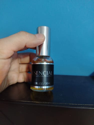 Cliente sosteniendo una botella de perfume H293 con líquido ámbar y etiqueta negra.