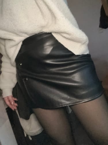 Une cliente porte le collant polaire effet transparent avec une jupe noire en similicuir.
