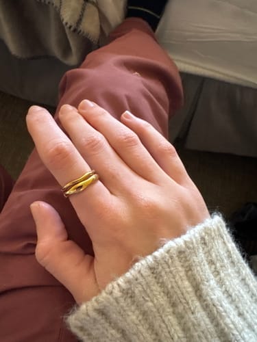 Customer's hand wearing the wavy, gold Madison Wave Ring Set on their finger.