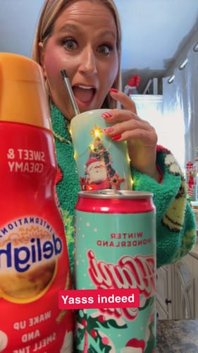 Customer excitedly shows off a festive can of Alani Nu Energy Drink, Winter Wonderland flavor, with a holiday cup.