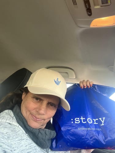 לקוחה מצלמת סלפי ברכב כשהיא חובשת את כובע המצחיה LOUDER by Émily בצבע קרם.