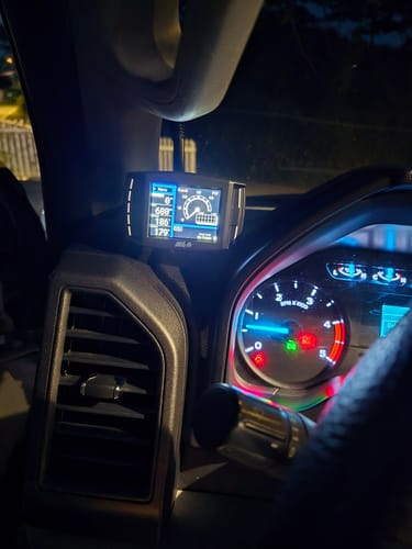 Customer's Mini Maxx Tuner V2 mounted in a truck's cab, with the screen illuminated at night displaying gauges.