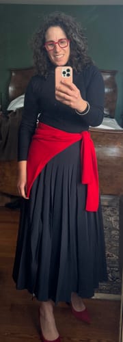 Reviewer wearing the black Plaka Skirt, styled with a red sweater tied at the waist and red shoes.