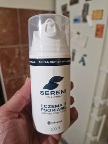 Vásárló a kezében tartja a SERENI Pikkelysömör és Ekcéma Krém fehér, pumpás flakonját.