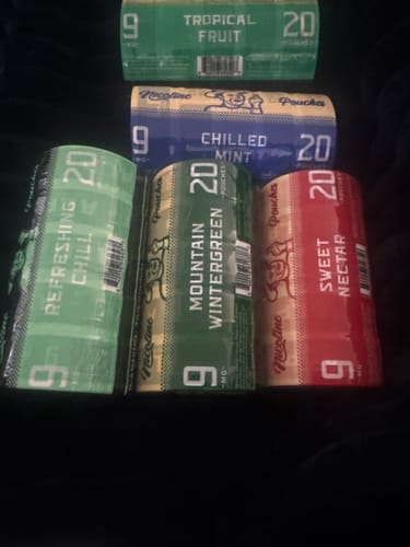 Customer displays packaging for various Alp nicotine pouches, including the red-labeled Sweet Nectar flavor.