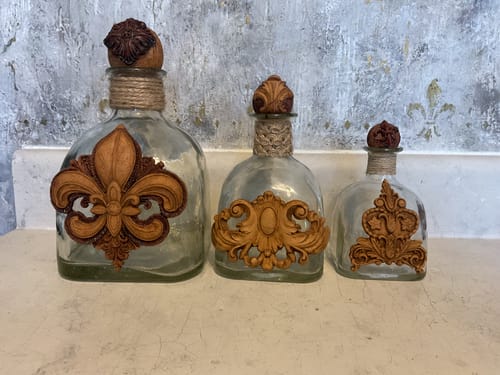 Reviewer's bottles decorated with ornate, brown WoodCast appliqués and twine.