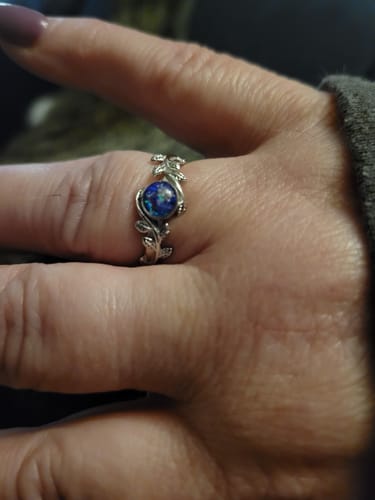 Customer wearing the Leaf Opal Cremation Ring, showing the silver leaf band and round blue opal stone.