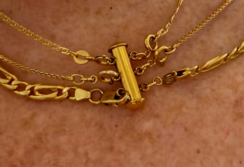 Close-up of a customer wearing the gold Necklace Spacer Detangler, connecting the clasps of three separate necklaces.