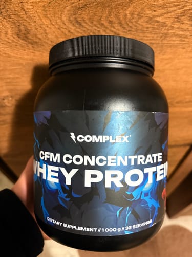 Customer holding a black tub of Complex CFM Concentrate Whey Protein.