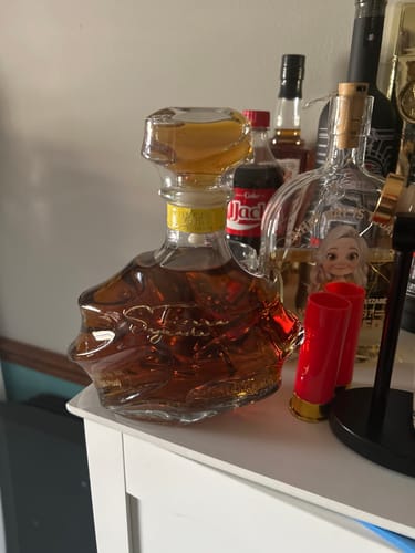 Customer's bottle of Tierra Sagrada Añejo Tequila on a white cabinet top among other bottles.